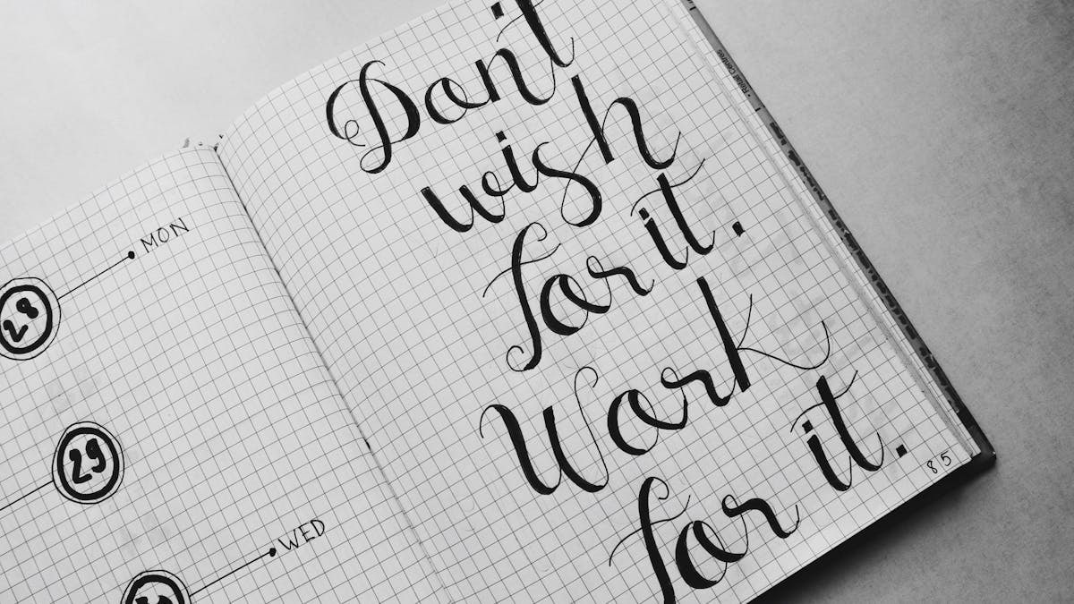 Close-up of motivational calligraphy on grid paper, inspiring message for productivity.